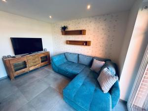 a living room with a blue couch and a flat screen tv at Ferienwohnung am Vechtedamm in Hoogstede