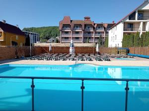 a large swimming pool with chairs and a building at Zakarpattya in Polyana