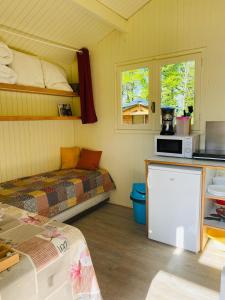 a small room with a bed and a microwave at Camping Le Vert-Bois - Corrèze in Saint-Martin-la-Méanne