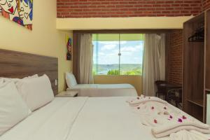a bedroom with a white bed with a window at Pedra do Sino Hotel in Piranhas +74 photos