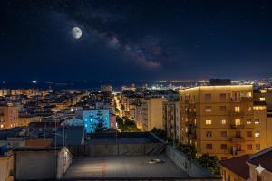 a view of a city at night with the moon at Torres House Suite & Rooms in Sassari