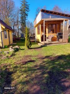a small yellow house with a porch on a yard at Pori-Kõrtsi talu in Nasja