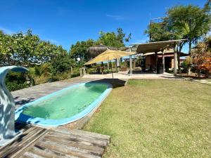 a hot tub in a yard next to a house at CAMALEÃO Ecopousada Ltda in Linhares