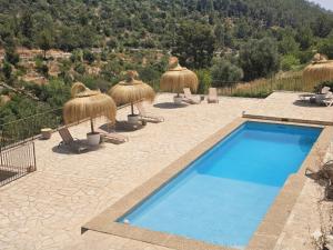 a swimming pool with straw umbrellas and lounge chairs at Agroturismo Finca Can Sec in Alaró