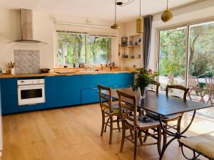 a kitchen with blue cabinets and a table with chairs at Villa de la Baume in Gémenos