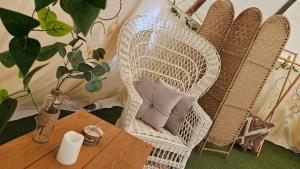 a wicker chair with pillows sitting next to a table at Casa Bella Teepees in Zújar