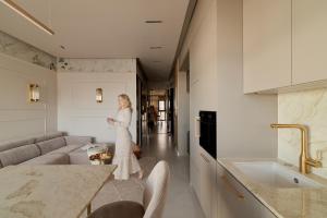 a woman in a white dress is standing in a kitchen at Sol Marina Riverview with free Parking & SPA additional by Downtown Apartments in Wiślinka