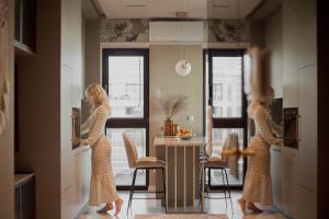 two women are standing in a kitchen preparing food at Sol Marina Riverview with free Parking & SPA additional by Downtown Apartments in Wiślinka