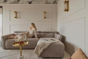 a woman sitting on a couch in a living room at Sol Marina Riverview with free Parking & SPA additional by Downtown Apartments in Wiślinka