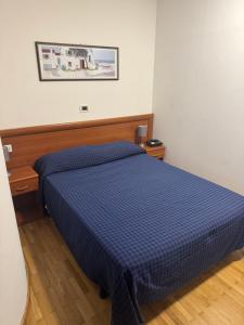 ein Bett in einem Zimmer mit einer blauen Bettdecke in der Unterkunft Hotel Belvedere in Sanremo