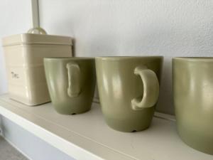 three coffee mugs sitting on a shelf at Cliff House, Azores splendid Ocean View in Horta