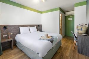 a bedroom with a large white bed and a table at Hôtel du Midi Plage in Palavas-les-Flots