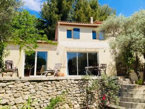a house with a stone wall and chairs at Villa de la Baume in Gémenos