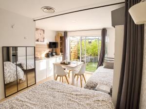 a bedroom with two beds and a table and a kitchen at Le Clos Lassagne -Terrasse privative - Climatisation - Lyon Sud - Brignais in Brignais