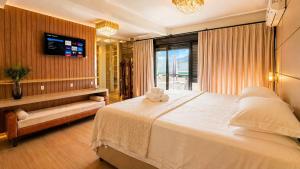 a bedroom with a large white bed and a television at Casa Premium no Centro - Passos do Alles Park in Pomerode +22 photos