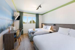 a hotel room with two beds and a desk at Hôtel du Midi Plage in Palavas-les-Flots