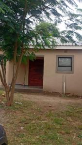 a house with a red door and a tree at Mkhuzewamanzi Accommodation in Mkuze +5 photos
