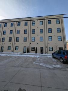 a large building with a car parked in a parking lot at Ruby Suite - New 2 bdrm 2bath near Mass! in Lawrence