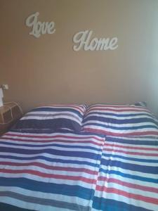a bed with a striped blanket and the words love home on the wall at Lena Lodge in Fonyód