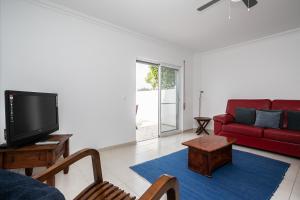 a living room with a red couch and a tv at Montesol by ALGARVEMANTA in Manta Rota