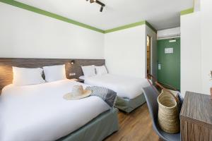 two beds in a hotel room with hats on the beds at Hôtel du Midi Plage in Palavas-les-Flots