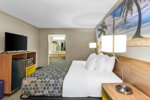 a hotel room with a bed and a flat screen tv at Rodeway Inn Owensboro South in Owensboro