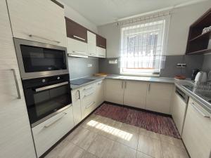 a kitchen with white cabinets and a black appliance at Chalupa GABO pre 15 osôb in Habovka