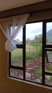 a window with a curtain and a view of a field at Mkhuzewamanzi Accommodation in Mkuze