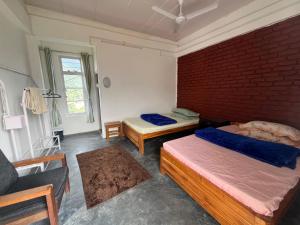 a bedroom with two beds and a brick wall at Saus Home in Khonoma