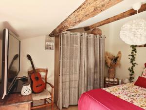 a bedroom with a bed and a guitar in a room at entre vignes et canal in Azille