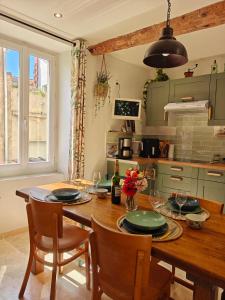 a kitchen with a wooden table with chairs and a dining room at entre vignes et canal in Azille +7 photos