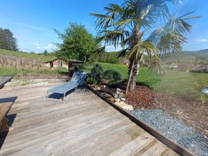 a wooden deck with a swing and a palm tree at Ti caz prairie in Marnoz +6 photos
