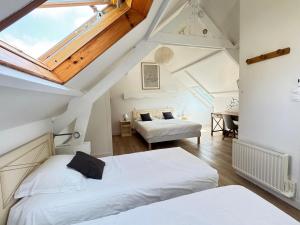 a attic bedroom with two beds and a piano at Logis Hôtel La Demeure du Perron in Quettehou