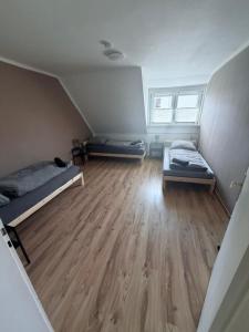 an attic room with two beds and a wooden floor at AlWi Apartment Wohnung 3 in Moringen
