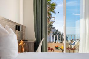 a hotel room with a bed and a view of a balcony at Hôtel du Midi Plage in Palavas-les-Flots