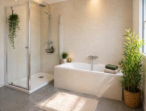 a bathroom with a tub and a shower with plants at La Maison des Écumes in Crozon +23 photos