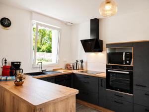 a kitchen with black cabinets and a wooden counter top at La Maison des Écumes in Crozon
