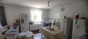 a kitchen with a table and a refrigerator and a window at Casa de praia castelhanos in Anchieta