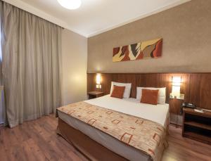 a bedroom with a large bed in a hotel room at Class Hotel Varginha in Varginha