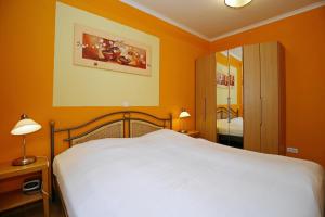 a bedroom with a white bed and orange walls at Dünenschloss Wohnung 1-34 in Kühlungsborn +19 photos