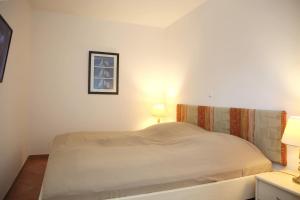 a white bed in a room with two lamps at Dünenschloss Wohnung 1-43 in Kühlungsborn +20 photos