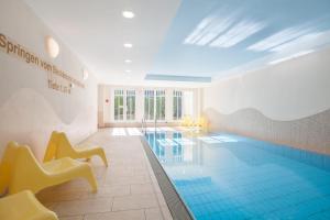 a swimming pool with yellow chairs in a room at Dünenschloss Wohnung 4-03 in Kühlungsborn