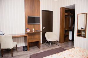 a room with a desk with a television and a chair at Class Hotel Varginha in Varginha