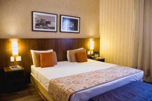a bedroom with a large bed in a hotel room at Class Hotel Varginha in Varginha