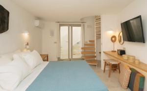 a bedroom with a bed and a desk with a television at Turquoise in Platis Gialos