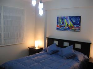 a bedroom with a bed and a painting on the wall at Bahiaxdia Paraguay in Bahía Blanca