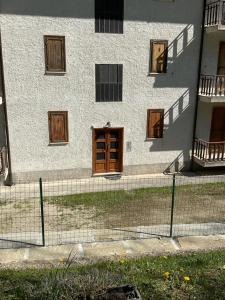 a building with wooden doors and a fence in front of it at Castori due in Prazzo