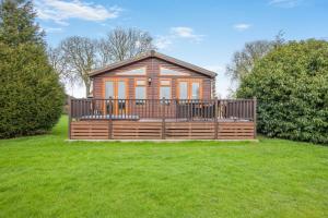 a wooden cabin with a large deck in the grass at Field View 1 bed-No Pets- Walnut in Eye