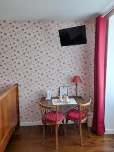 a dining room table with two chairs and a tv on a wall at Chambres d'Hôtes et Table d'Hôtes- Valentine 44 in Sainte-Mère-Église