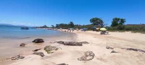 a beach with people and people with umbrellas at Casa de praia castelhanos in Anchieta